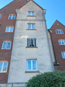 Algae growth on commercial building render in Kent after wet winter