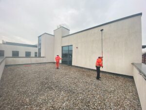 Technician soft washing commercial cladding in Surrey using low pressure system