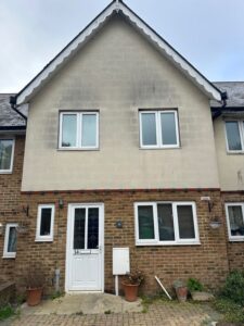 Uncleaned render showing staining and cracking on commercial wall in Surrey